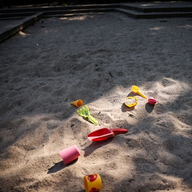 Spielzeug liegt in einer Sandkiste auf einem Spielplatz als Symbol dafür, dass in der Stadt 500 Kita-Plätze fehlen.