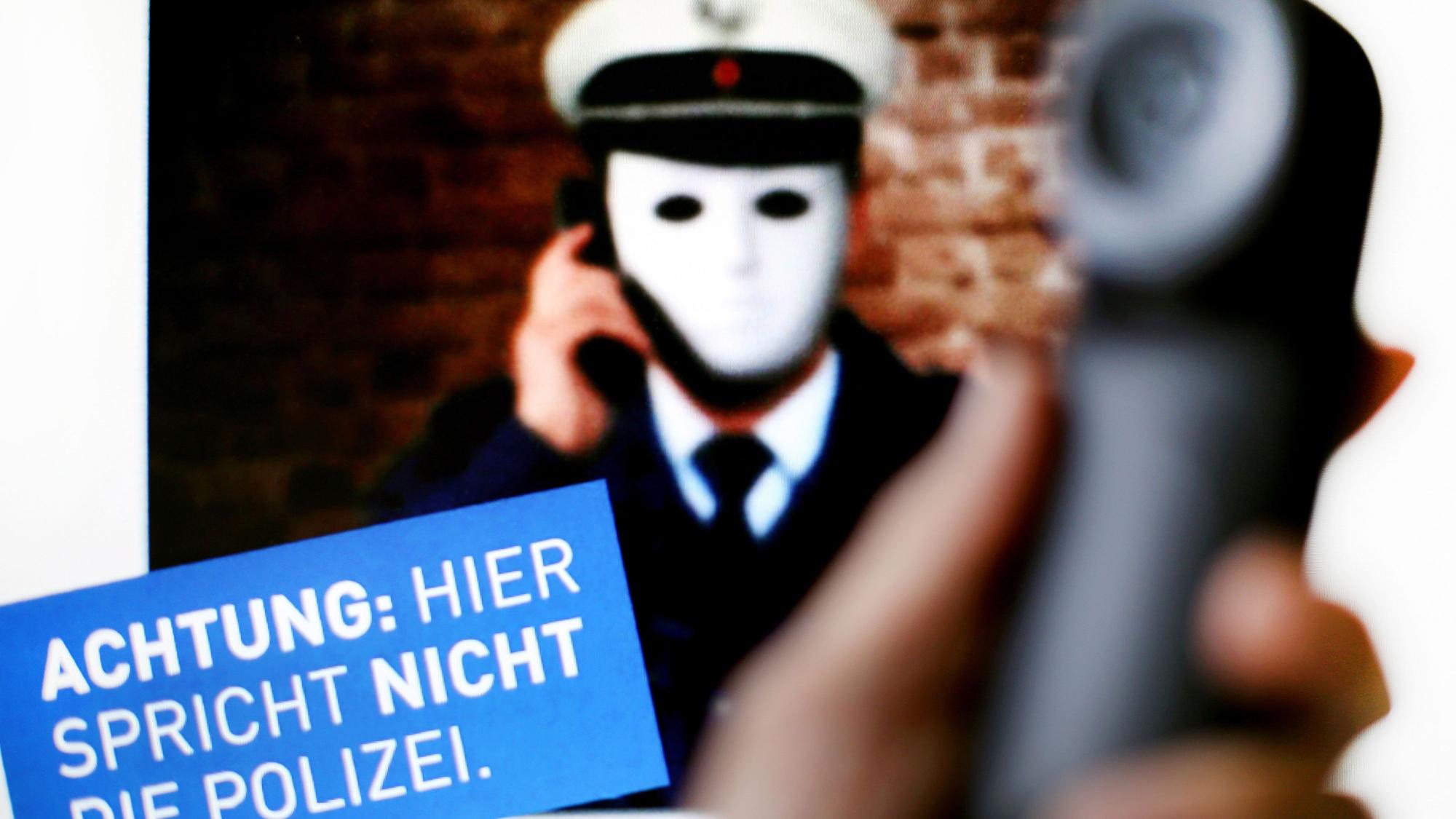 ILLUSTATION - Ein Telefonhörer ist am 11.10.2017 in Düsseldorf (Nordrhein-Westfalen) vor einem Plakat der Polizei NRW mit der Aufschrift "Achtung: Hier spricht nicht die Polizei" zu sehen. Das Plakat der Polizei warnt vor Betrügern, die sich am Telefon als Polizisten ausgeben.