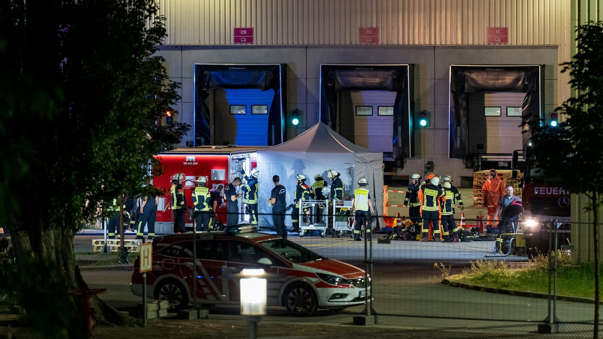 14.08.2023, Hessen, Wiesbaden: Rettungskräfte sind in der Nacht auf einem Werksgelände im Einsatz.