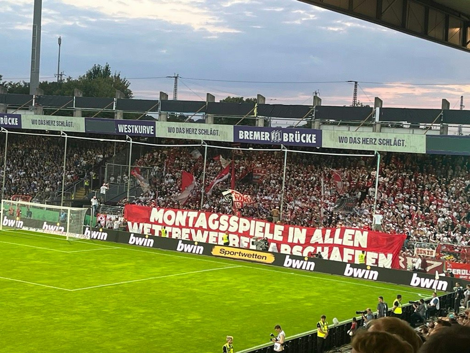 FC-Fans in Osnabrück kritisieren mit einem Banner die Spielansetzung am Montagabend.