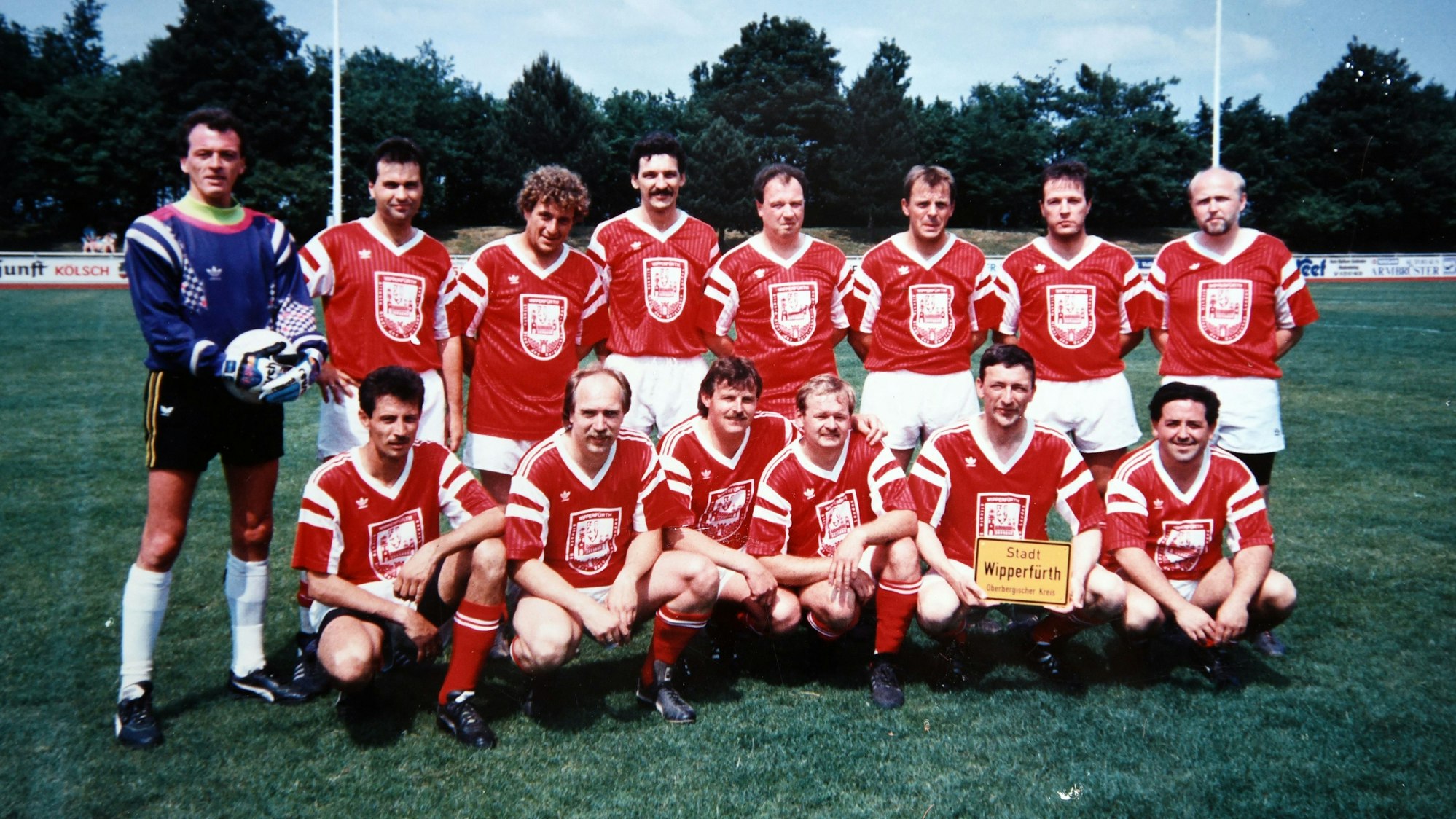 Ein altes Foto einer ehemaligen Fußballmannschaft, die zum Mannschaftsfoto auf einem Fußballplatz zusammengekommen ist.