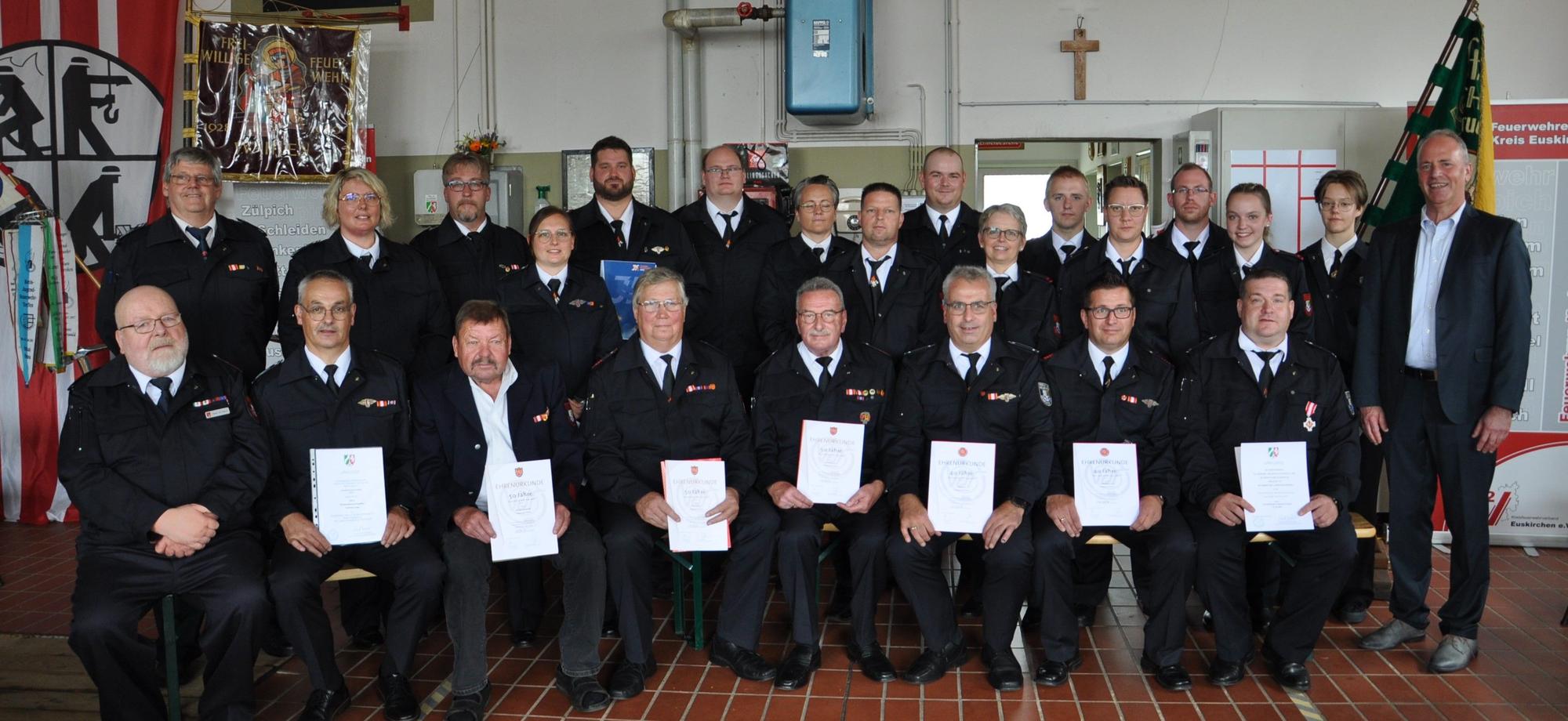 Eine Gruppe Feuerwehrleute hält Auszeichnungen in den Händen.
