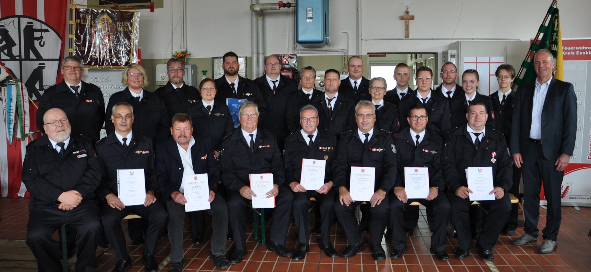 Eine Gruppe Feuerwehrleute hält Auszeichnungen in den Händen.