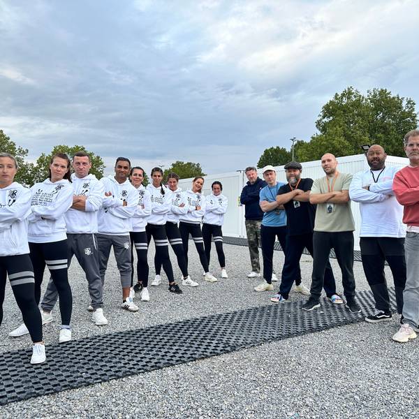 Das Bild zeigt die jungen Sportler aus Brühl, die mit verschränkten Armen in einer Reihe posieren. Daneben bilden die Musiker der Gruppe Deichkind eine Reihe.