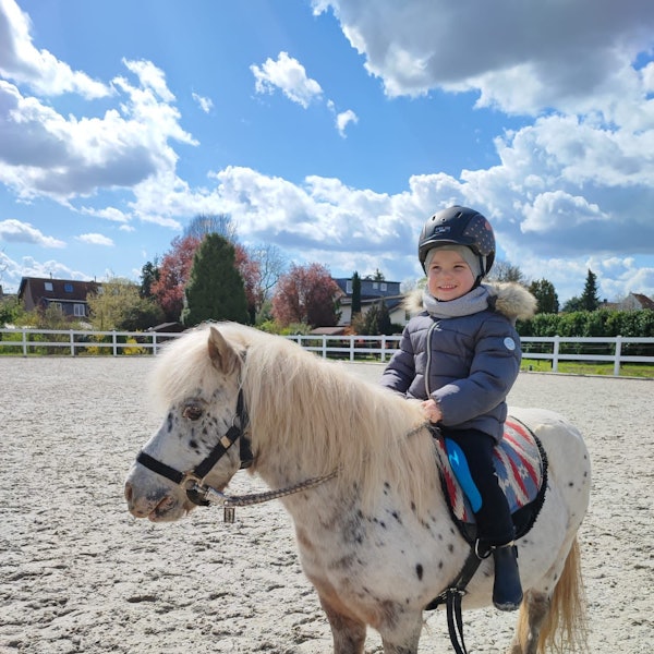 Ein Kind sitzt auf einem Pony.