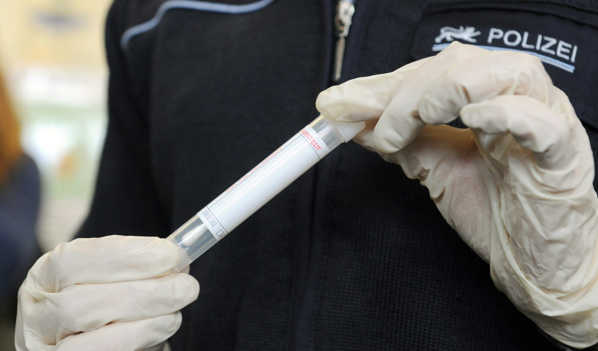 Eine Polizistin hält ein Wattestäbchen für eine DNA-Probe.