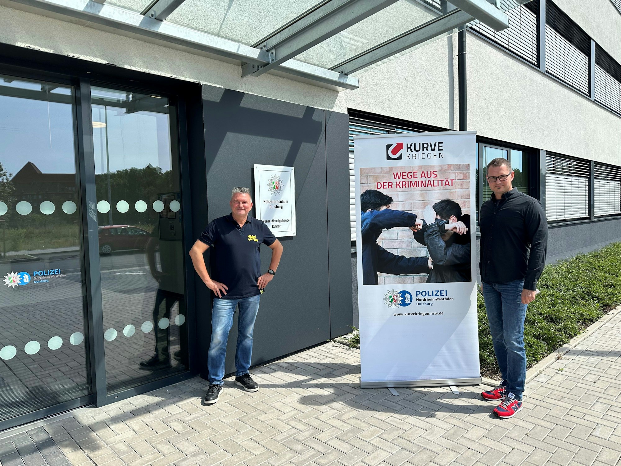 Polizeihauptkommissar Torsten Meldau (links) und Pädagogische Fachkraft Markus Witalinski (rechts) von der Initaitive "Kurve Kriegen" vor dem Polizeipräsidium Duisburg