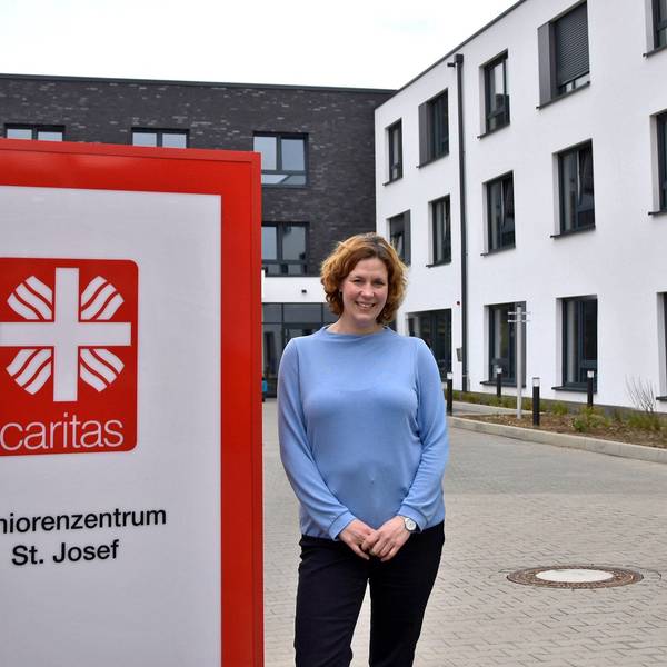 Ein Mann und eine Frau stehen neben dem Schild eines Seniorenheims.
