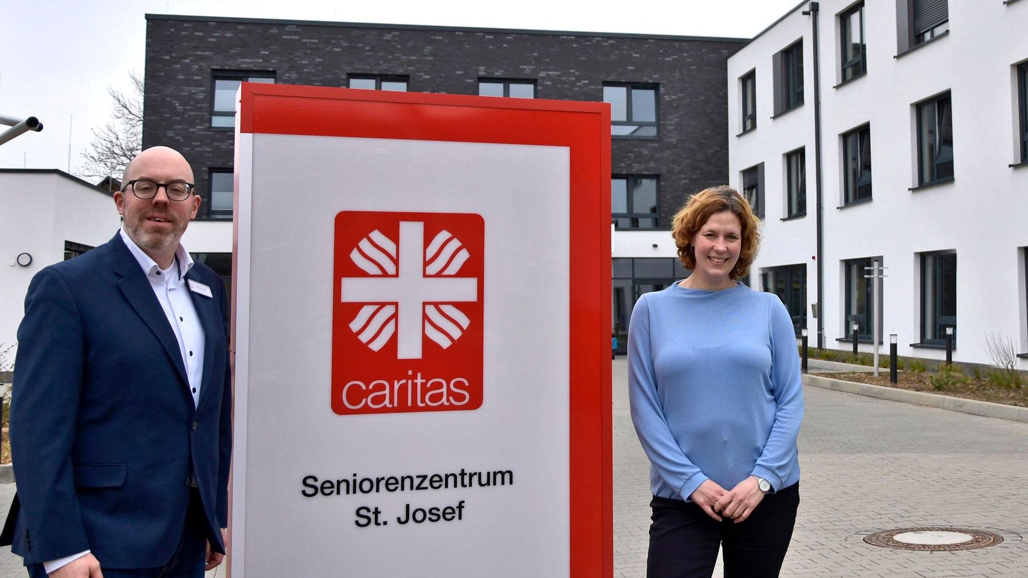 Ein Mann und eine Frau stehen neben dem Schild eines Seniorenheims.