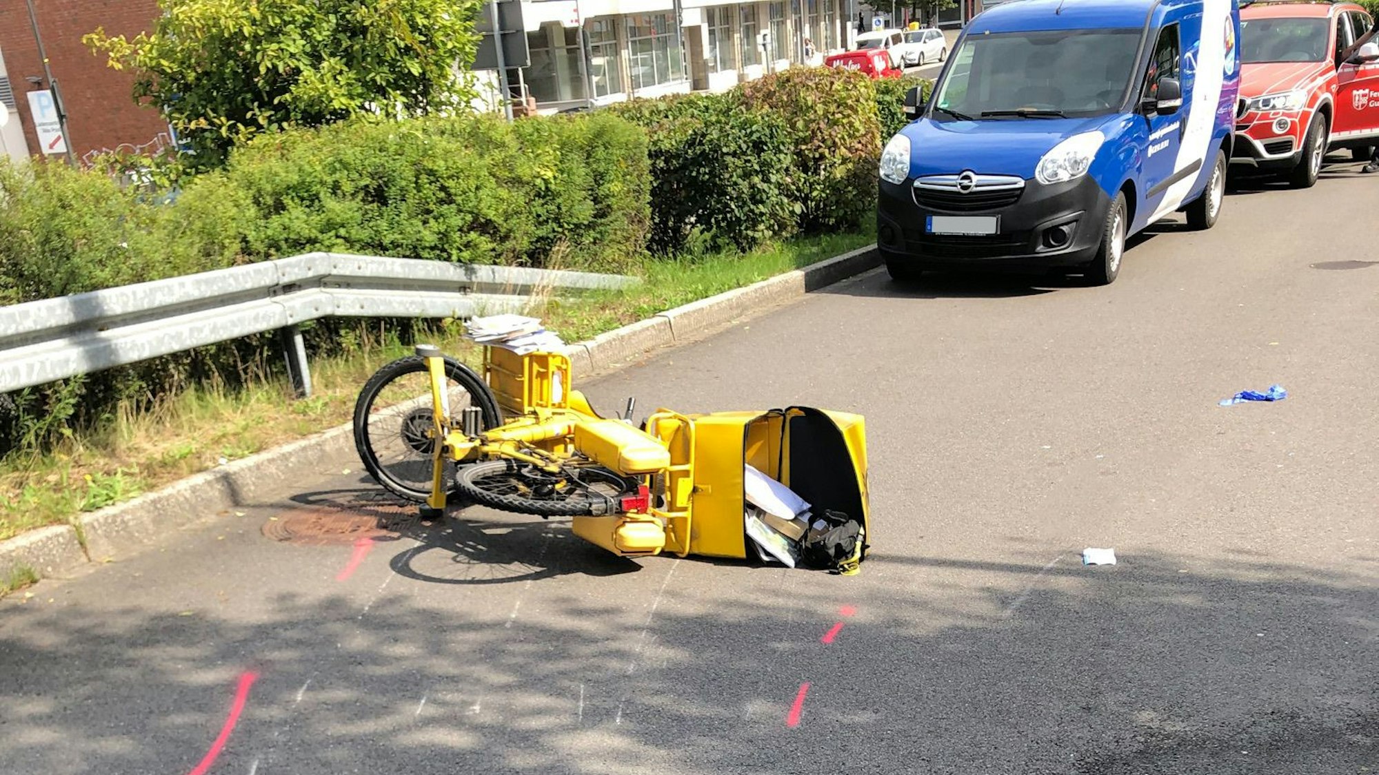 Das Fahrrad einer Postbotin liebt auf einer Straße, auf der Markierungen zu sehen sind.