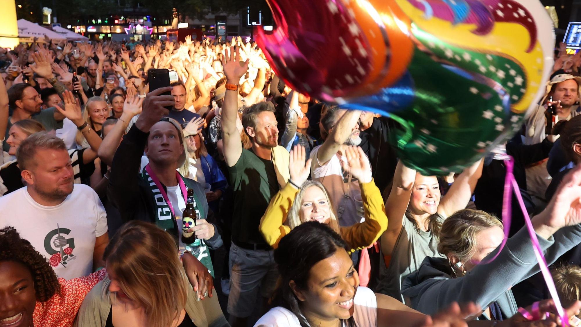 Viele Menschen tanzen vor einer Bühne.
