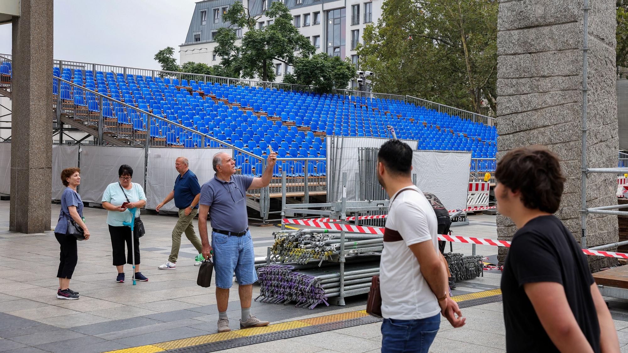 Passantinnen und Passanten stehen vor einer aufgebauten Zuschauertribüne.