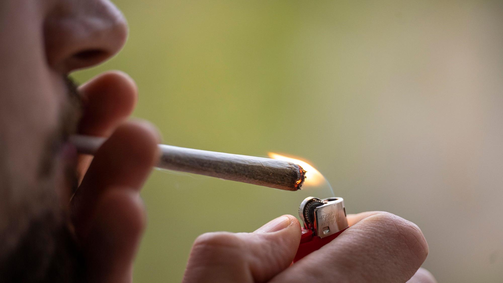 Ein Mann zündet sich einen Joint an. (Symbolbild)