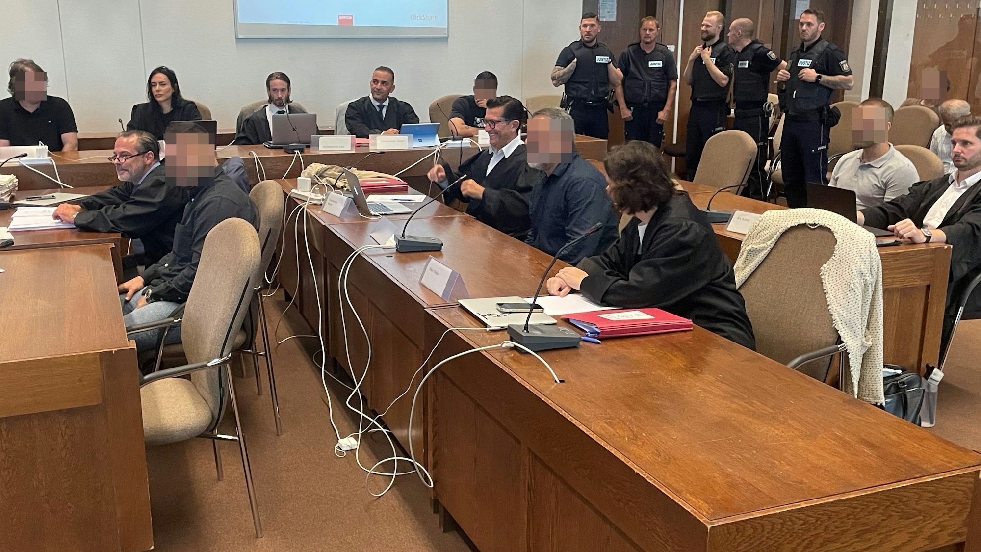 Die mutmaßliche Drogenbande mit Verteidigern und Wachtmeistern beim Prozessauftakt im Kölner Landgericht.