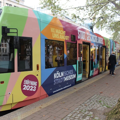 Das Bild zeigt eine bunte KVB-Bahn auf dem Neumarkt in Köln.