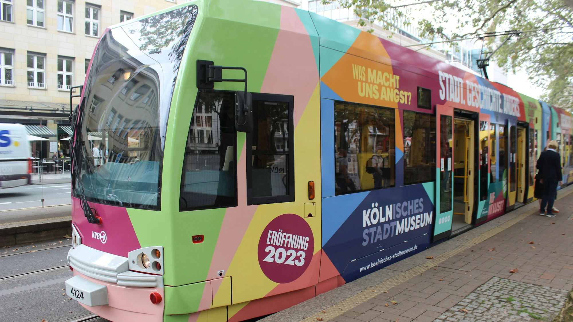 Das Bild zeigt eine bunte KVB-Bahn auf dem Neumarkt in Köln.