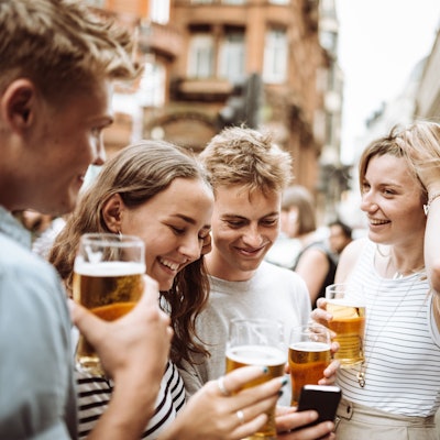 Junge Menschen trinken Bier bei einem Straßenfest.