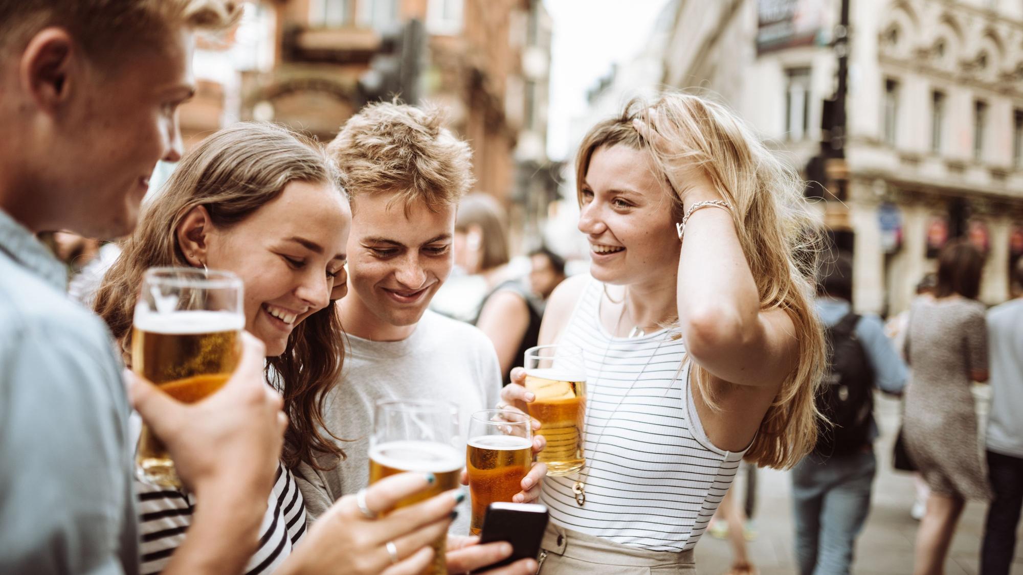 Junge Menschen trinken Bier bei einem Straßenfest.