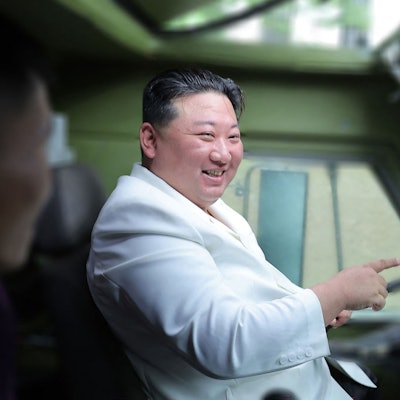 Kim Jong Un sitzt lachend in einem Militärfahrzeug am Steuer.