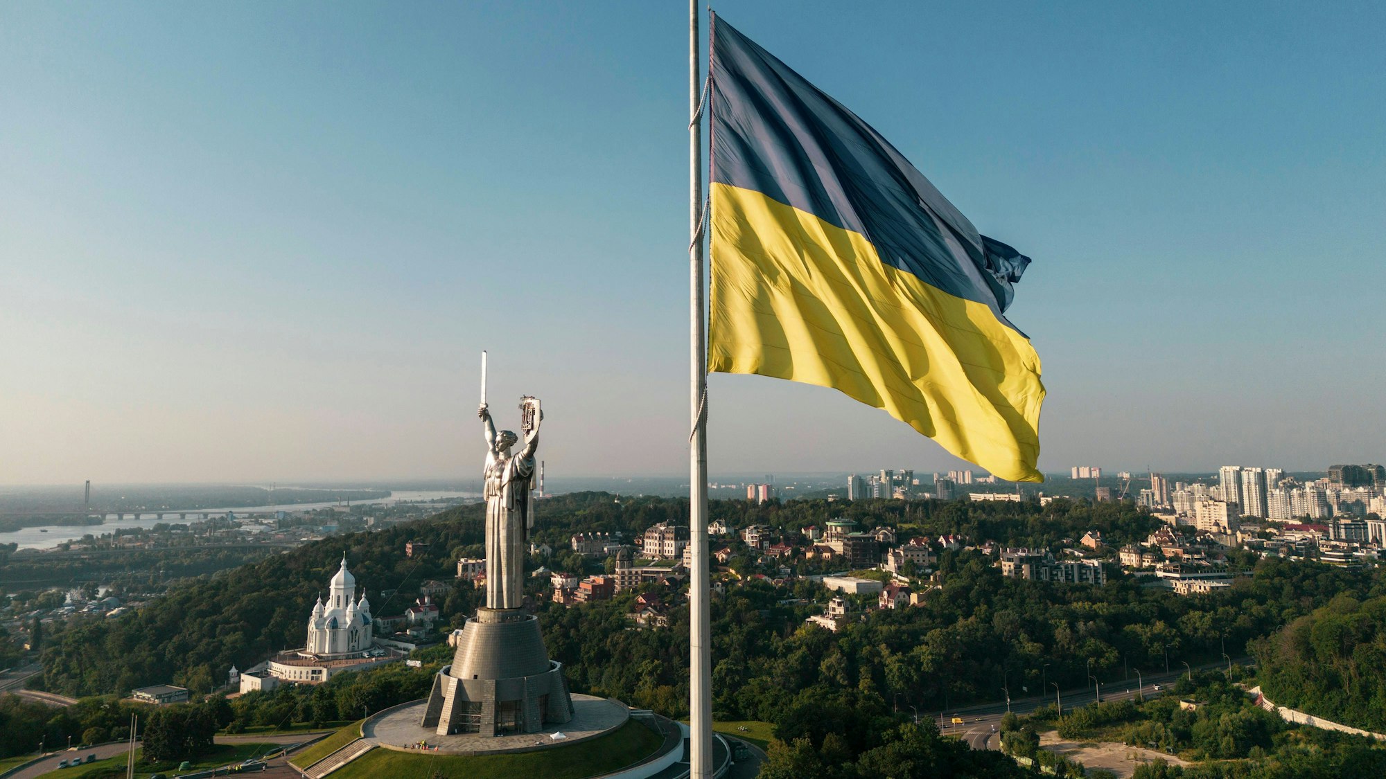 Eine ukrainische Flagge weht nahe dem Denkmal von „Mutter Heimat“ in Kiew im Wind. (Symbolbild)