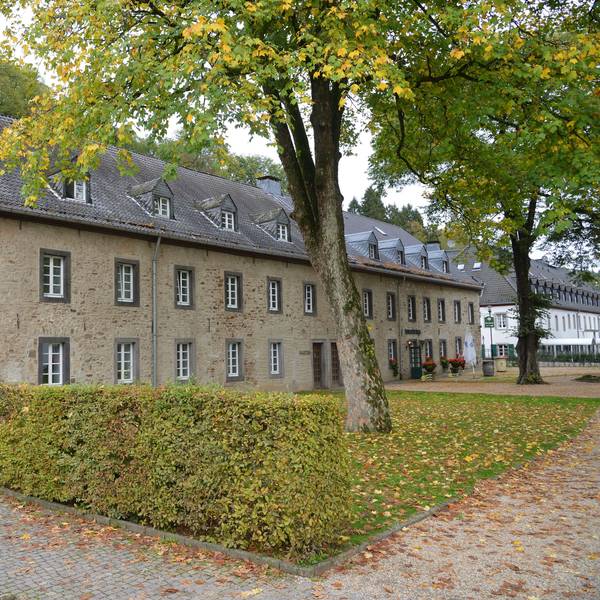 Ein historisches Gebäude mit dem Schriftzug Altes Brauhaus. Lindenbäume, davor eine Hecke.