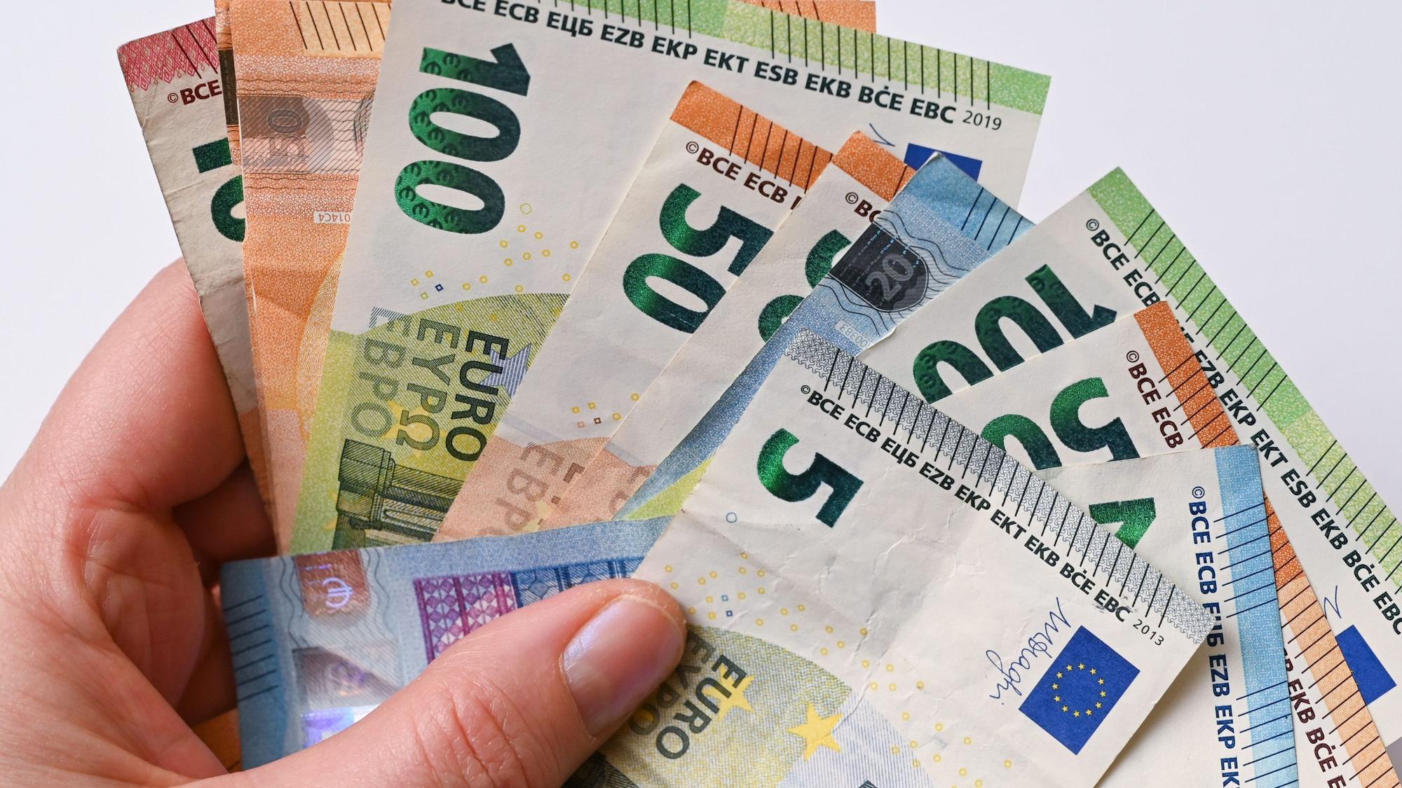Das Foto zeigt viele Geldscheine in einer Hand.