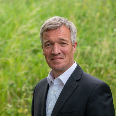 Ein Mann im Anzug lächelt in die Kamera.