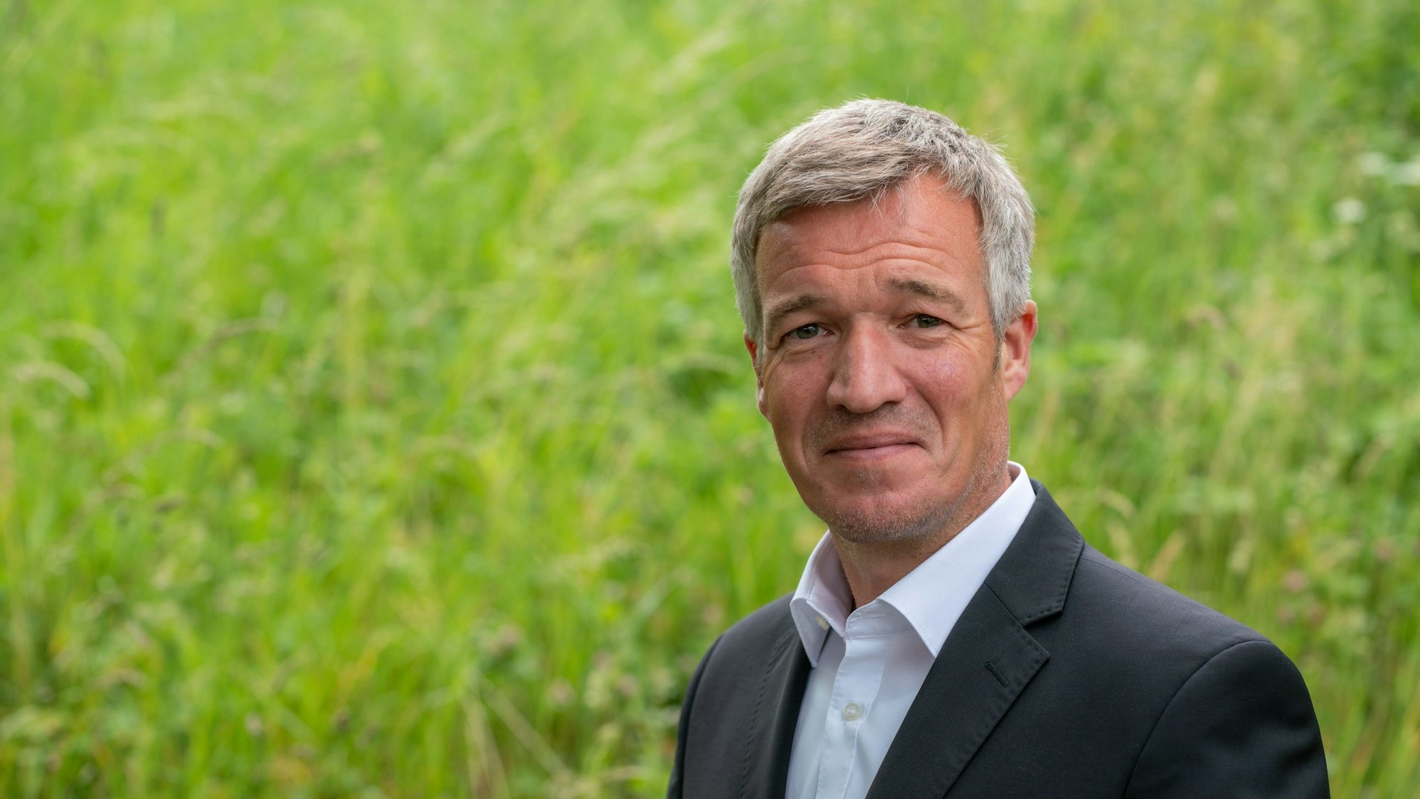 Ein Mann im Anzug lächelt in die Kamera.