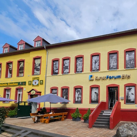 Auf dem Foto ist das Kunstforum Eifel mit den Bildern in den Fensteröffnungen zu sehen.