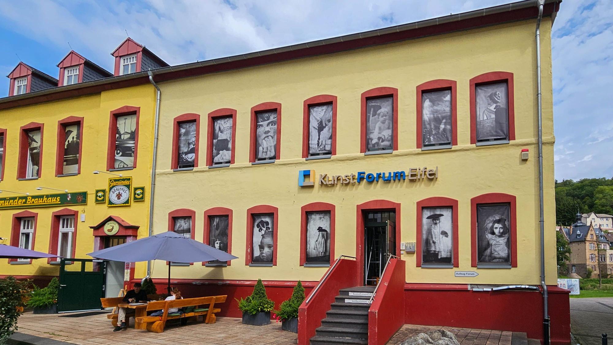 Auf dem Foto ist das Kunstforum Eifel mit den Bildern in den Fensteröffnungen zu sehen.