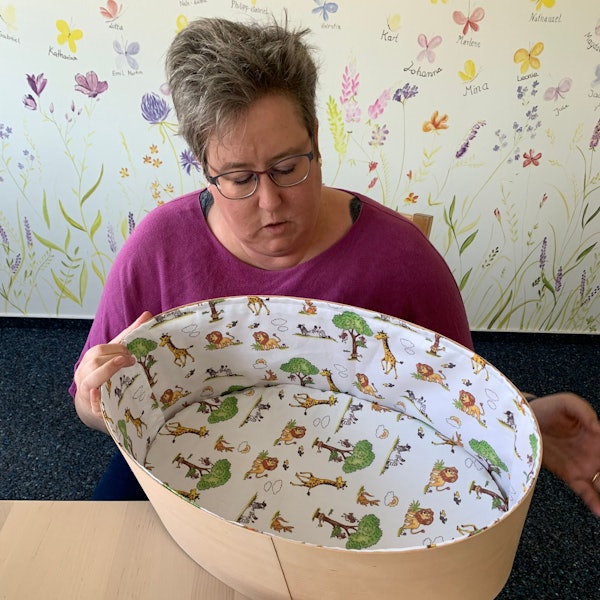 Eine Frau blickt in einen leeren Kindersarg.