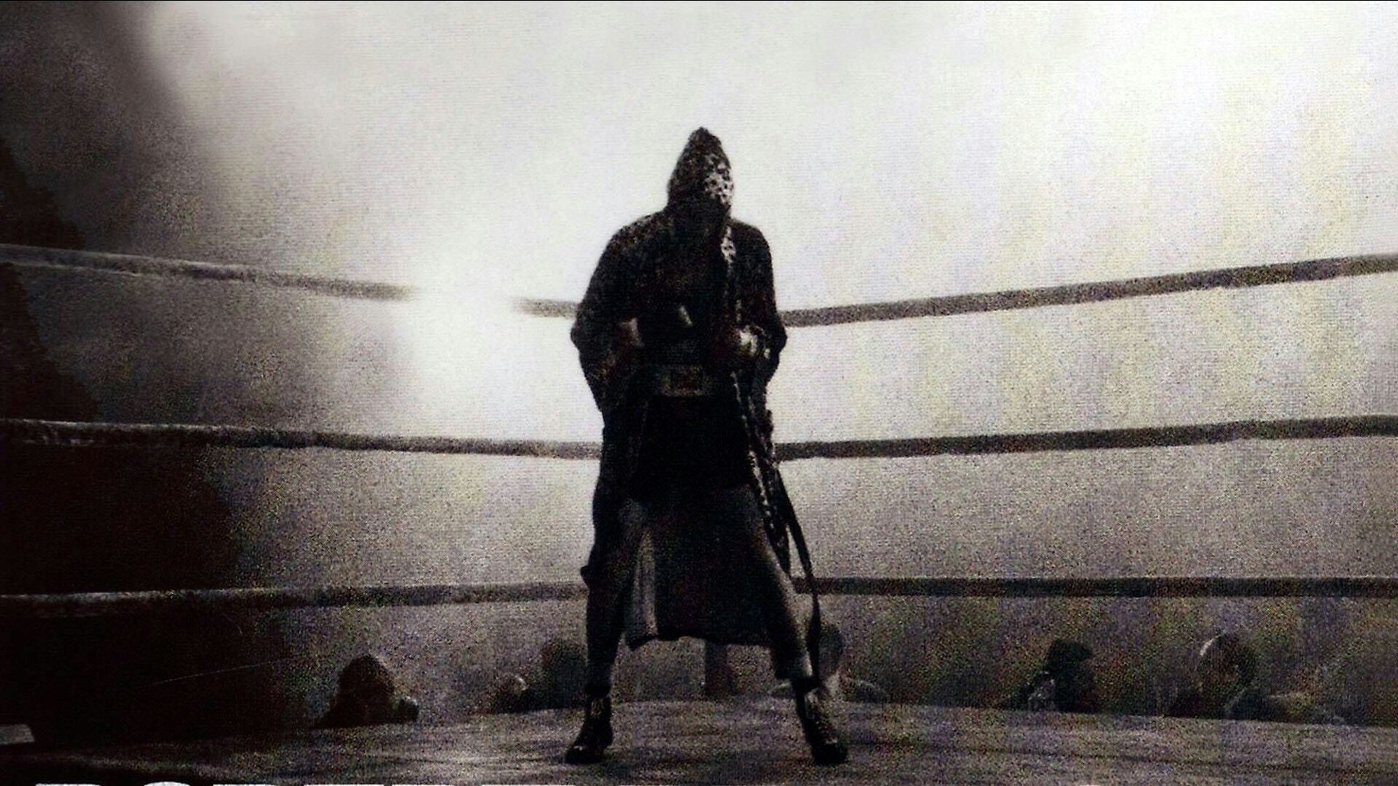 Ein Boxer tänzelt im Ring, er trägt einen Mantel mit Kapuze.