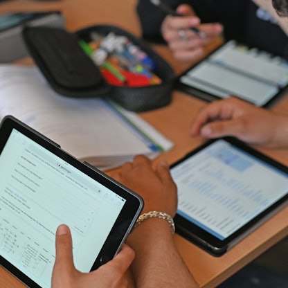 Kinder sitzen in einer Klasse und arbeiten mit ihren Tablets.
