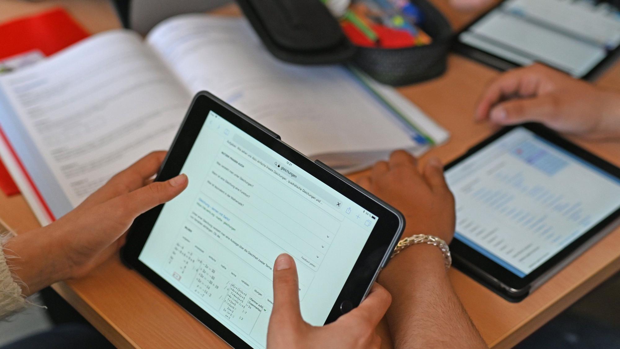 Kinder sitzen in einer Klasse und arbeiten mit ihren Tablets.