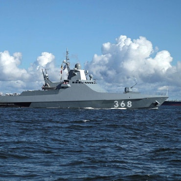 Das russische Patrouillenboot „Wassili Bykow“ bei einer Marine-Parade nahe St. Petersburg. Im Hintergrund ist ein Frachter zu sehen. Das Boot feuerte im Schwarzen Meer Warnschüsse ab, bevor Soldaten einen Frachter stürmten. (Archivbild)