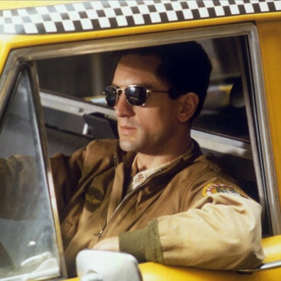 Ein Mann mit Sonnenbrille sitzt am Steuer eines Taxis.