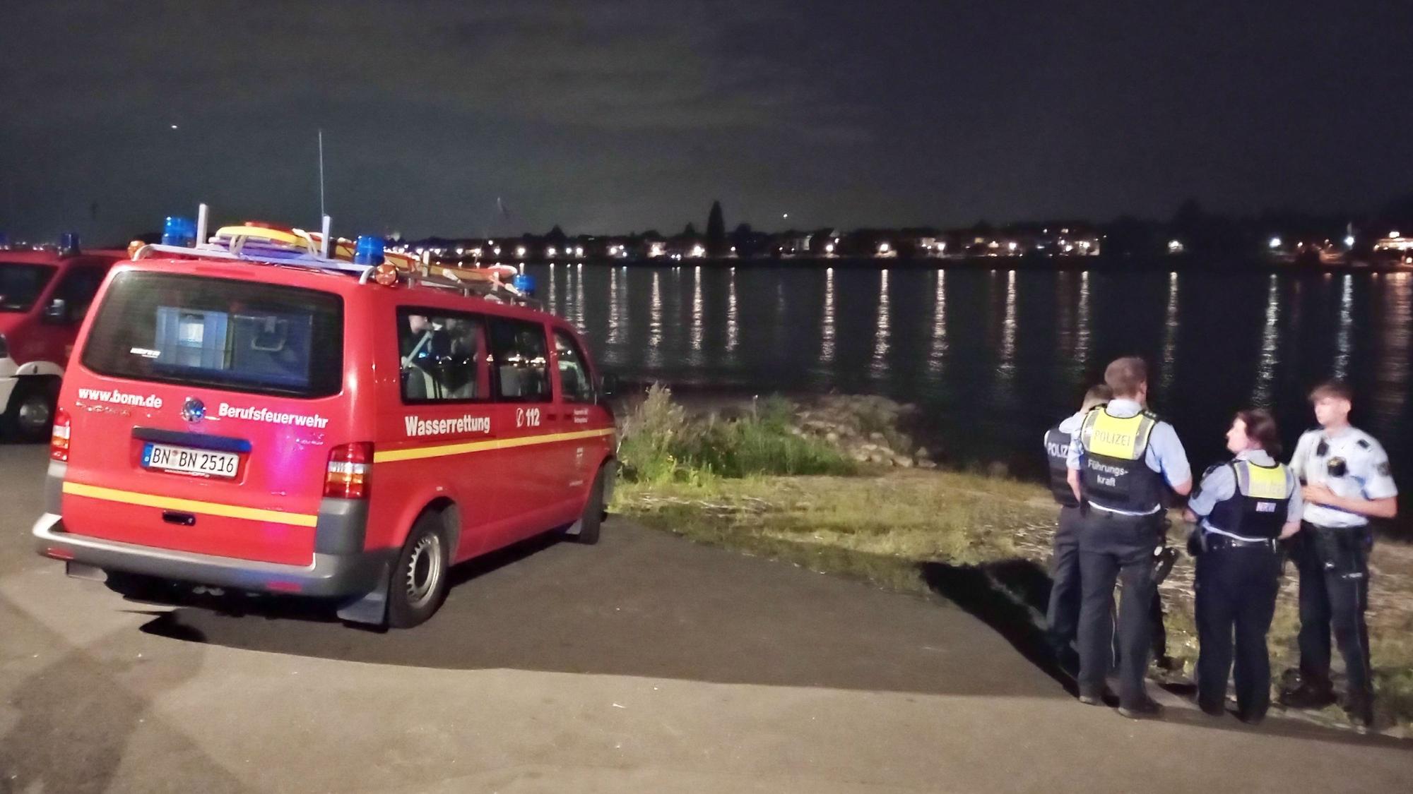 Rettungskräfte blicken auf das Wasser.