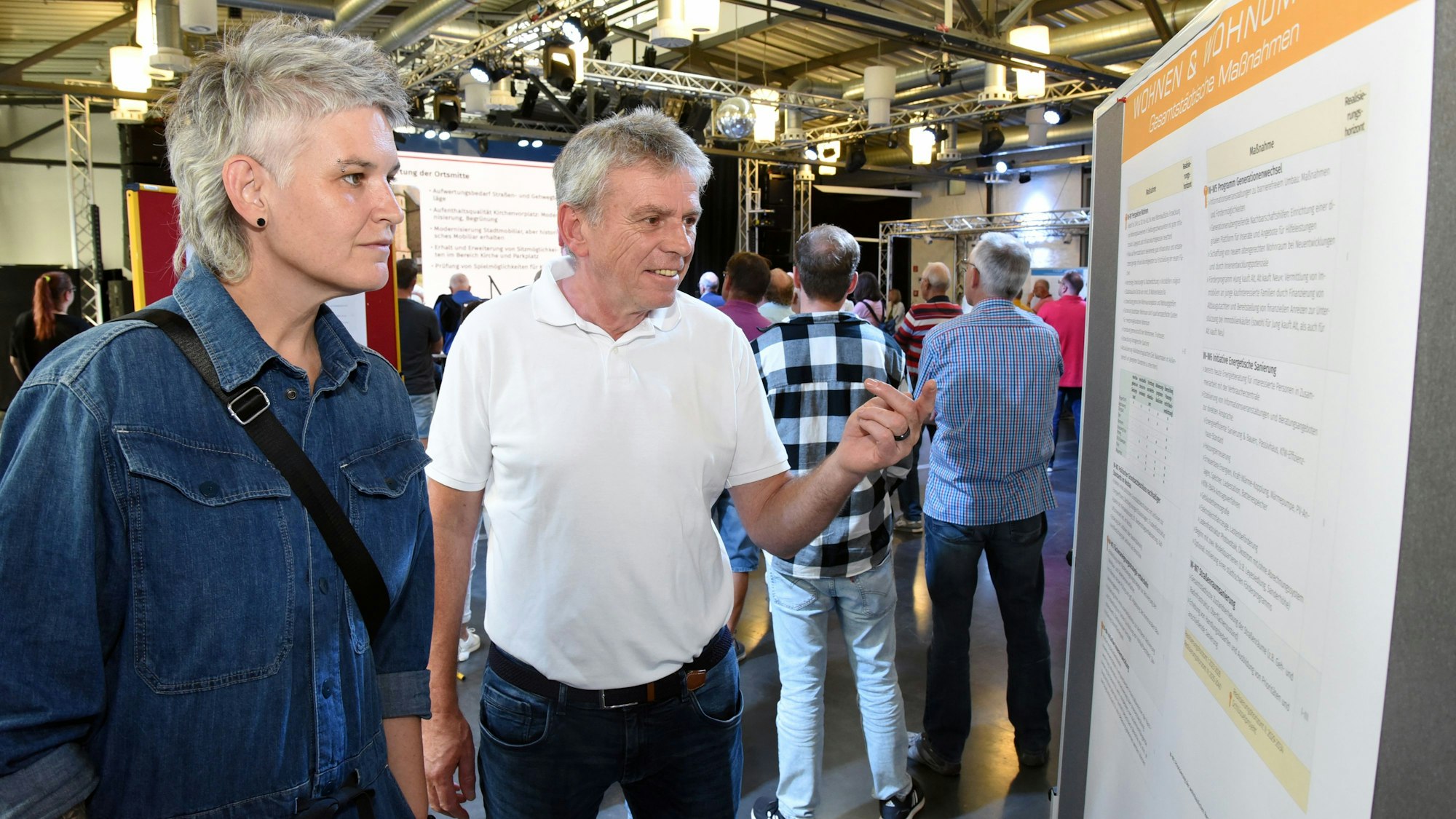Zwei Personen stehen vor einem Schaubild und informieren sich über das Integrierte Stadtentwicklungskonzept.