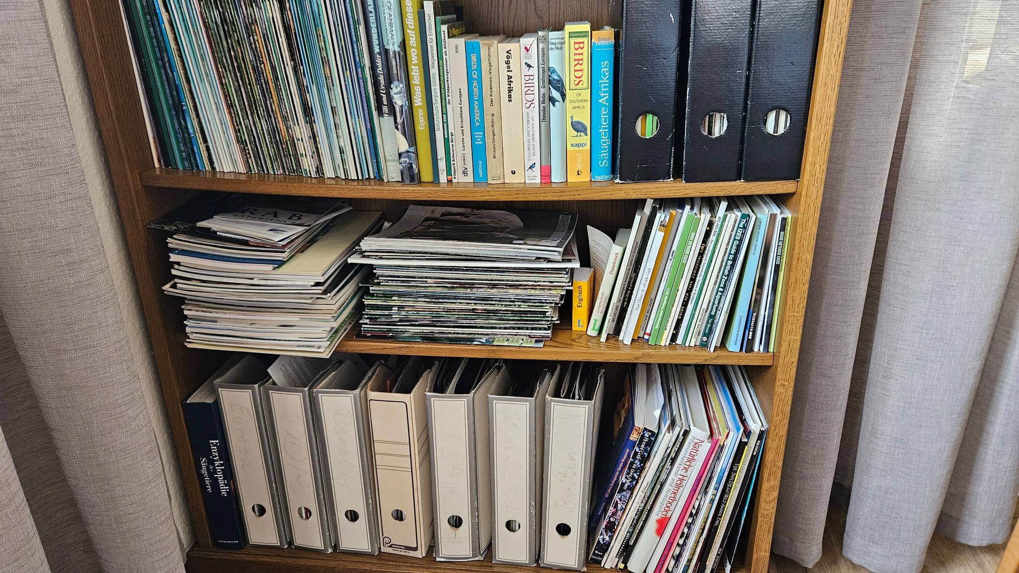 Auf dem Foto ist ein volles Regal mit Büchern und Heften zu sehen.