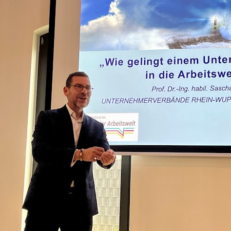 Sascha Stowasser, Chef des Instituts für Angewandte Arbeitswissenschaft, steht vor einer Folie.