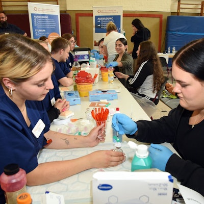 Eine Mitarbeiterin des Gesundheits- und Bildungszentrums Oberberg erklärt einer Schülerin an einem Stand ihre Arbeit.