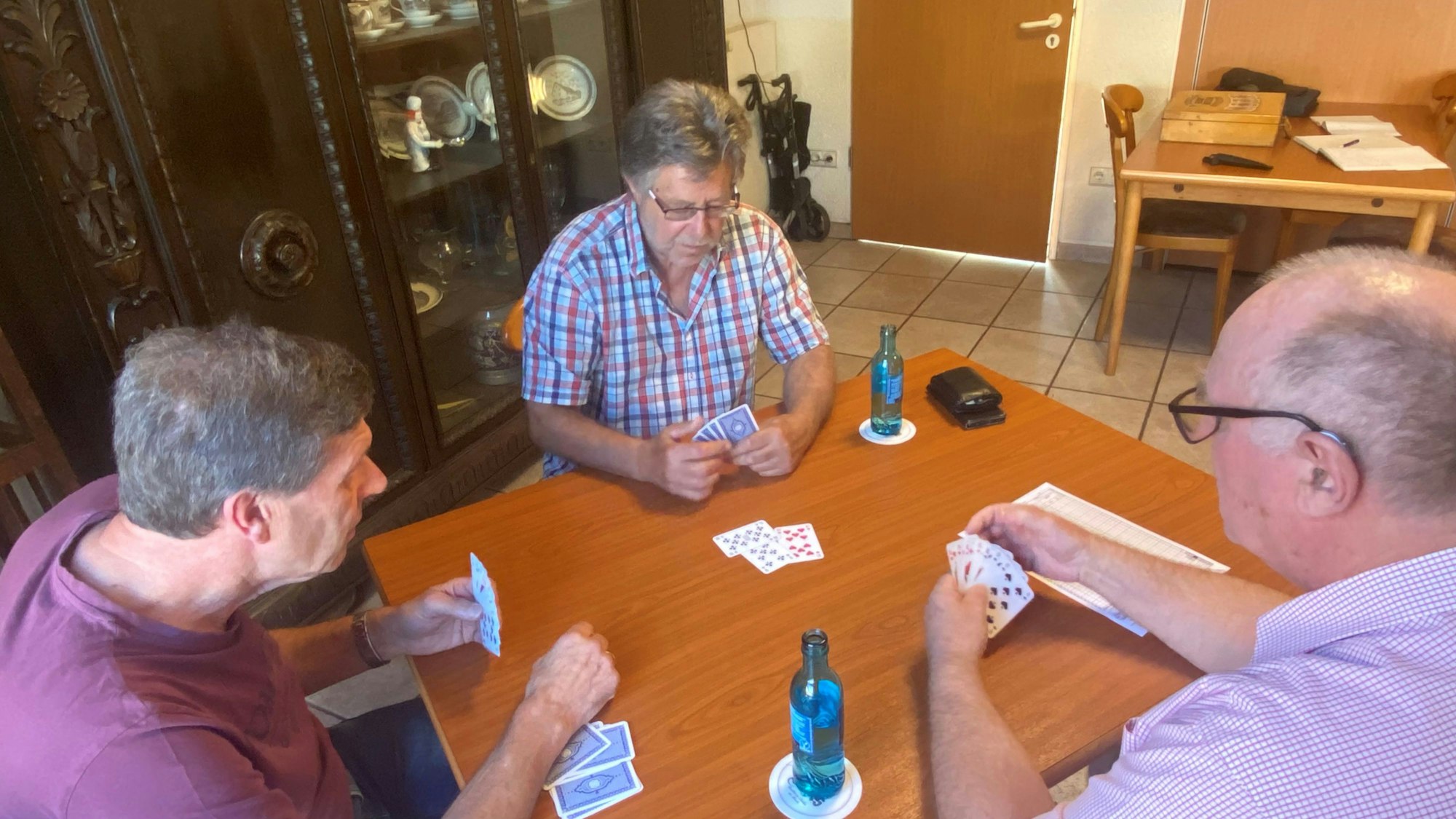 Herbert Lehmann, Peter Metzner und Hubert Siminski sitzen am Tisch und spielen Skat.