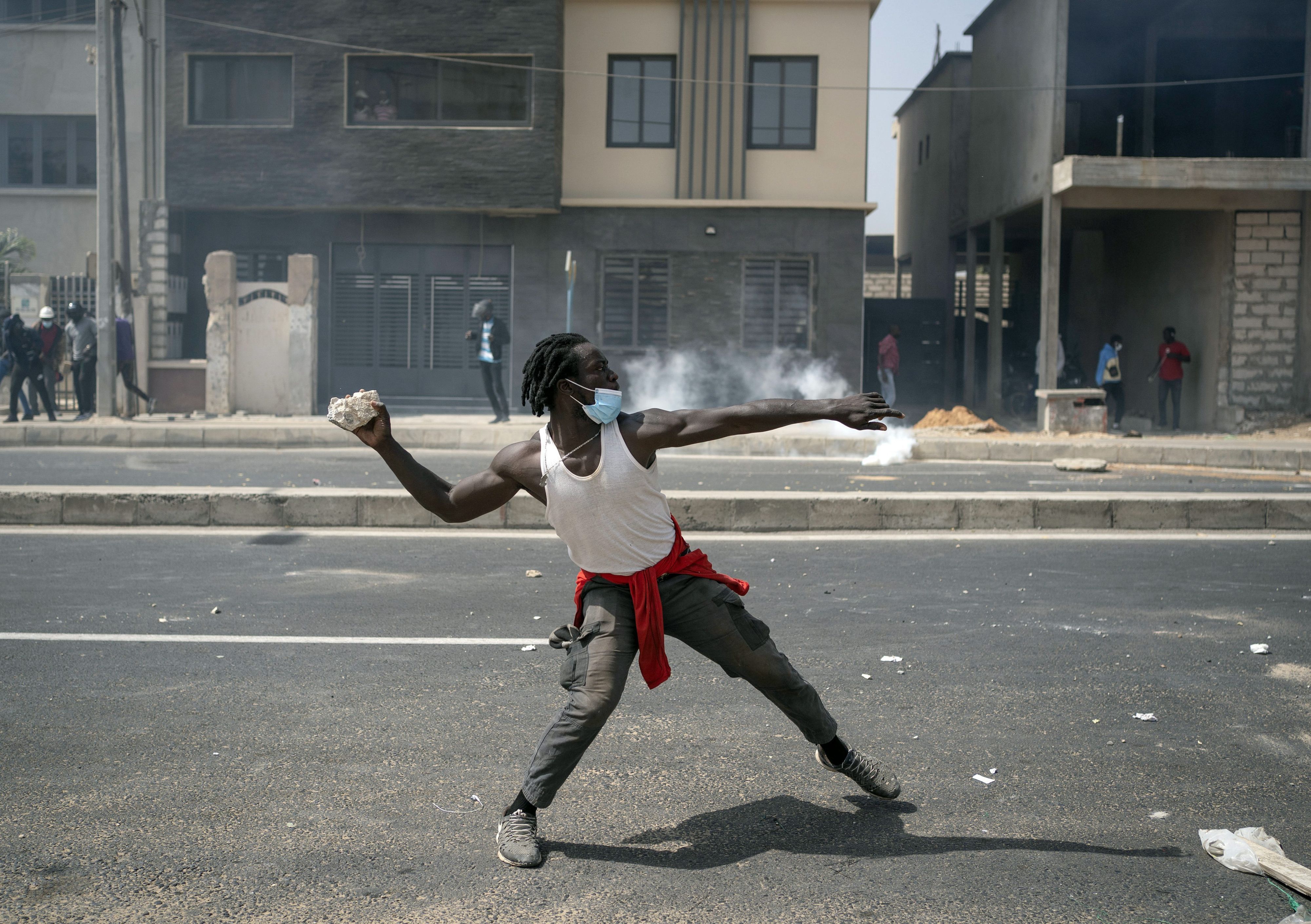 Ein Demonstrierender wirft einen Stein auf die Polizei, während den Aufständen für Ousmane Sonko im Senegal.