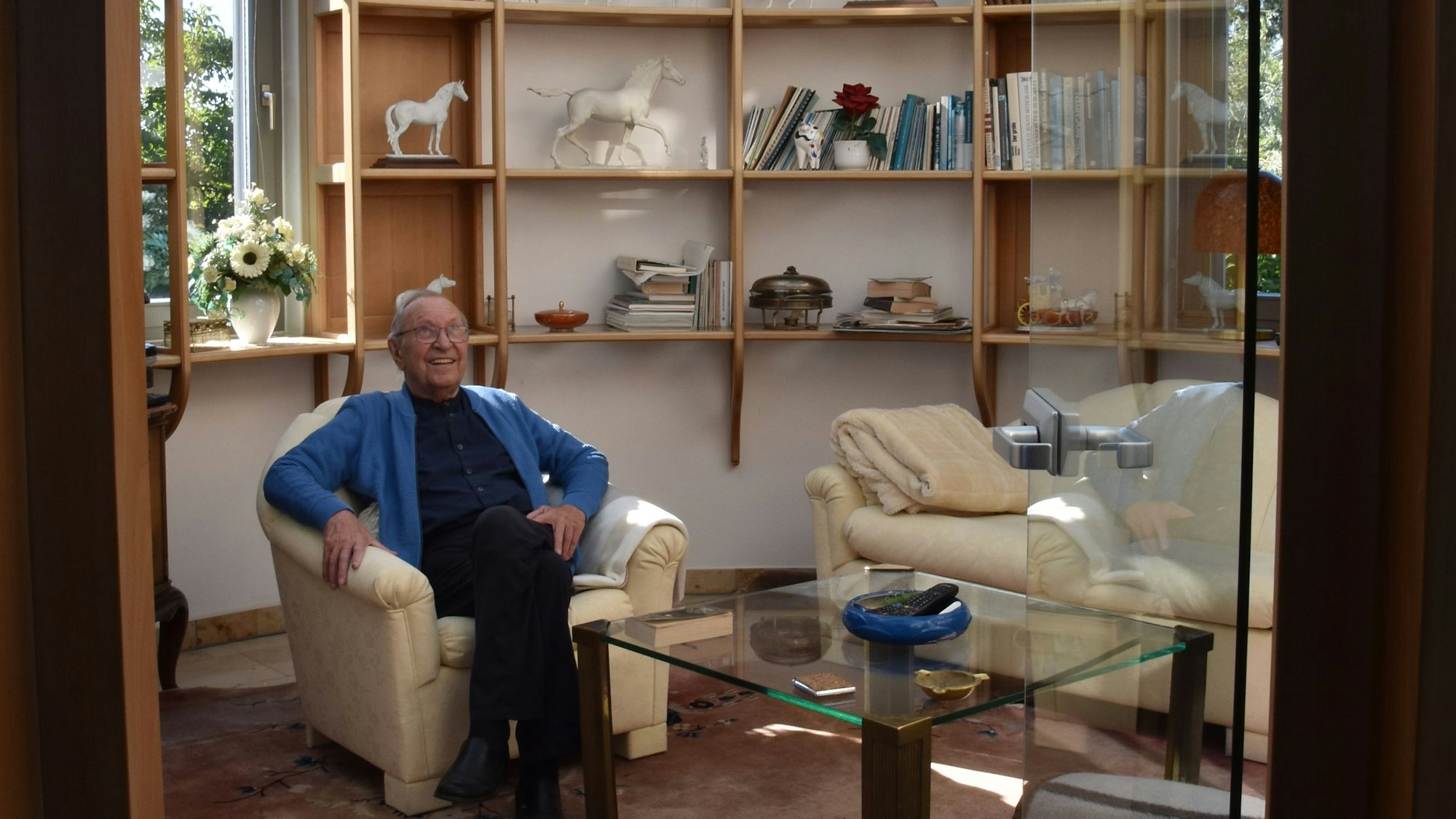 Ein älterer Mann sitzt in seinem Wohnzimmer.