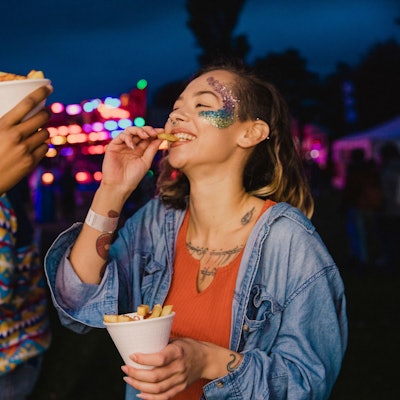 Eine kleine Gruppe von Freunden teilt sich auf einem Fest eine Portion Pommes.