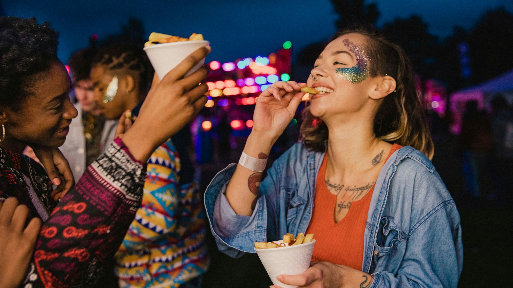 Eine kleine Gruppe von Freunden teilt sich auf einem Fest eine Portion Pommes.