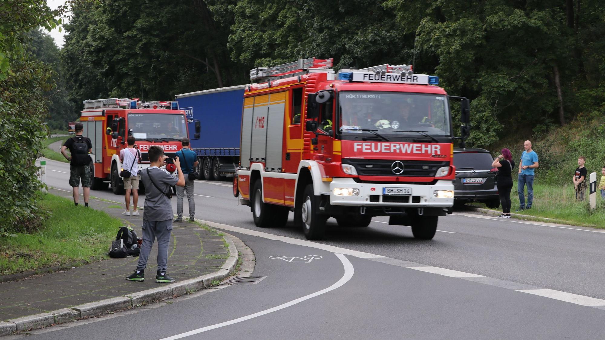 Jugendliche fotografieren vom Straßenrand aus Feuerwehrwagen.