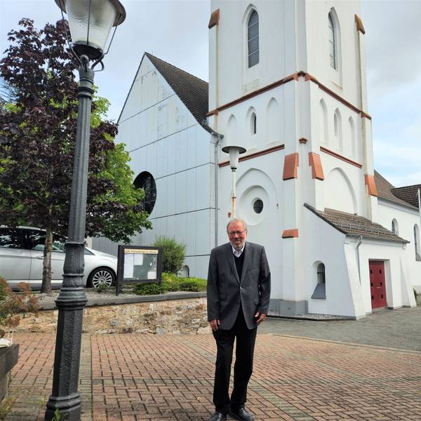 Pfarrer Hans-Joachim Hellwig steht vor der Kaller Pfarrkirche.