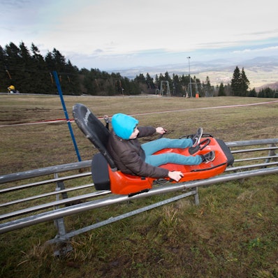 Ein Junge saust auf der Wasserkuppe (Hessen) die Sommerrodelbahn entlang.