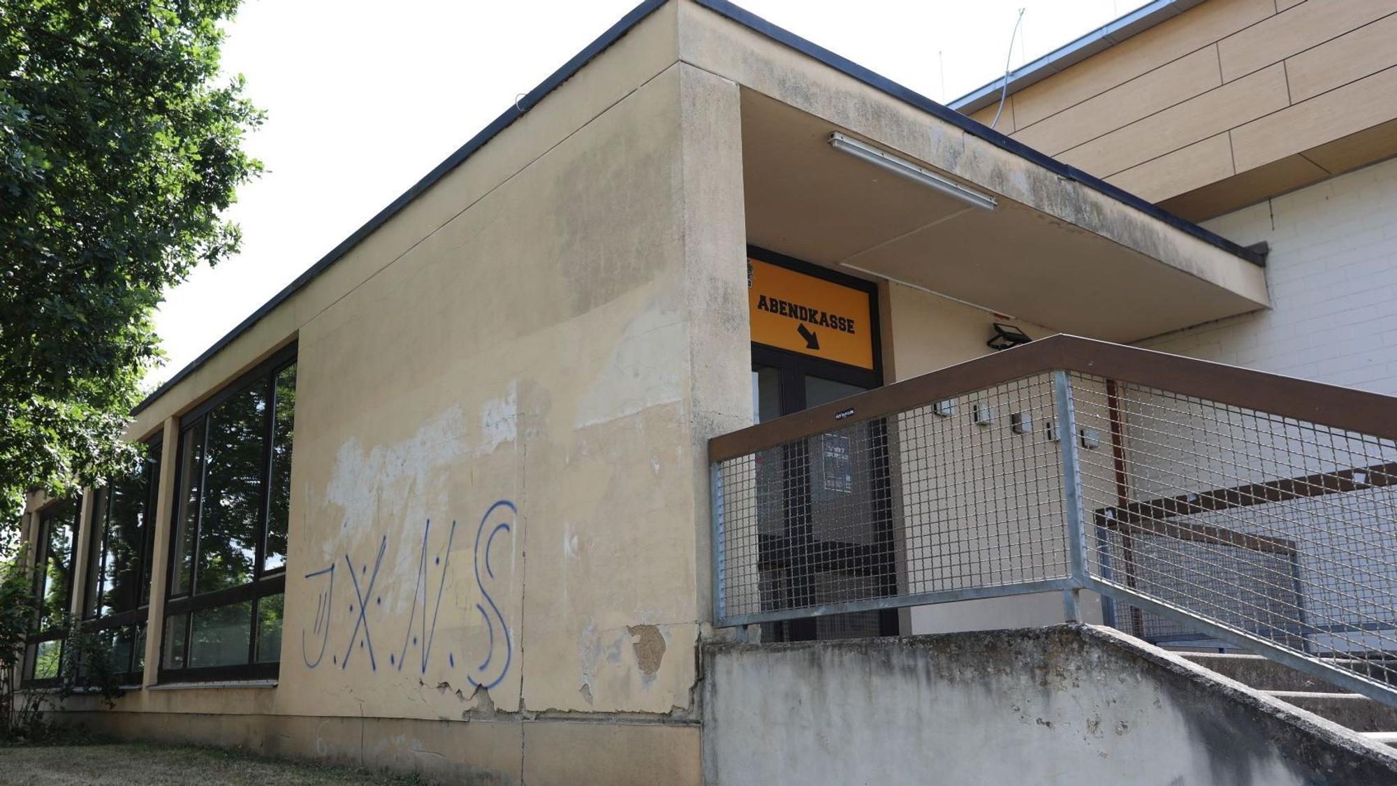 Blaue Graffiti-Buchstaben sind an der Fassade des Eingangsbereichs der Menzenberger Halle zu sehen.